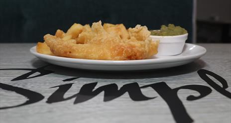 Image is of a plate of fish, chips and mushy peas