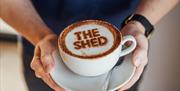 Image of a cup of coffee with the shed written on it
