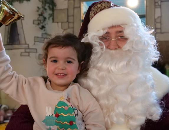 Pictured is Santa Claus with a Child ringing a bell.