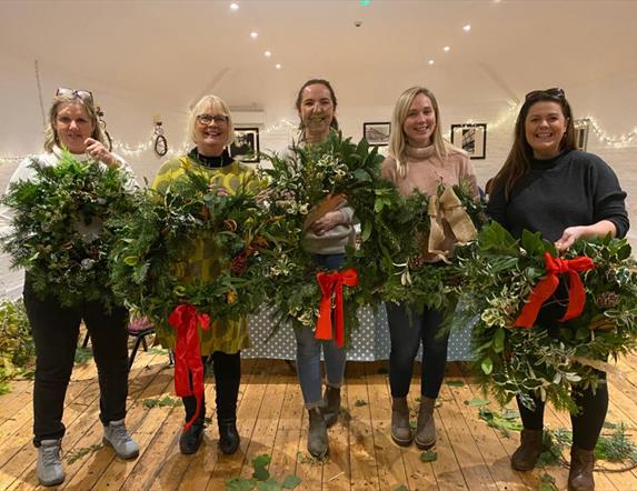 Image shows 5 people holding their decorated wreaths.