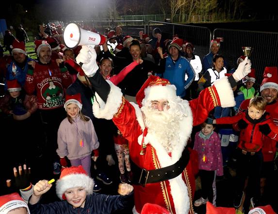 Picture of Santa Clause and surrounding children 
 wearing Santa hats.