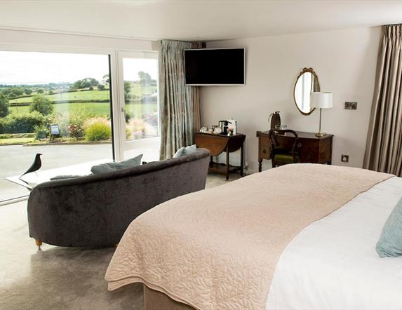 Shows image of double bedroom with large window looking out at countryside view