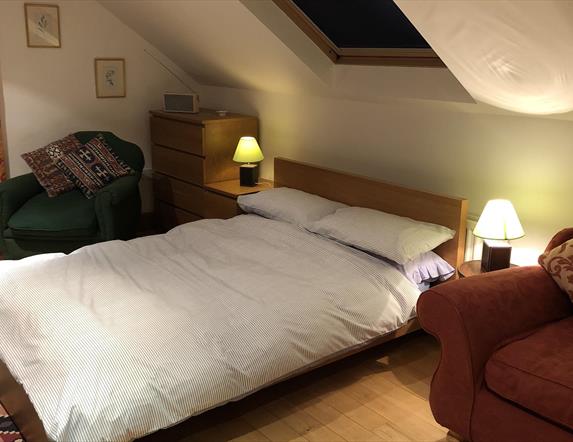 Image shows bedroom with double bed, 2 side tables and 2 chairs. Skylight above the bed.