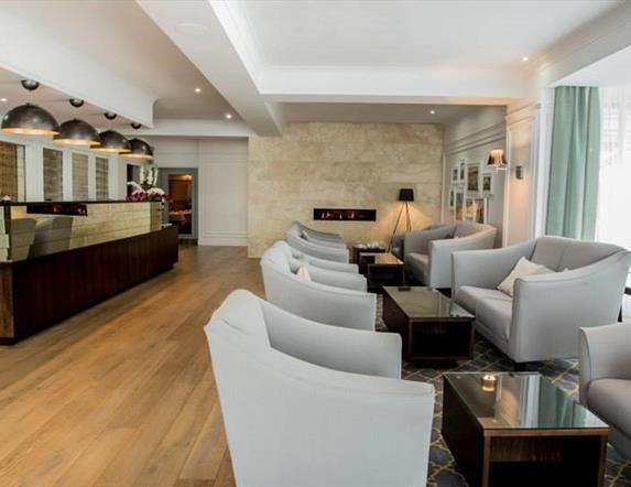 Image shows receptionist at desk in reception area. Also chairs and coffee tables