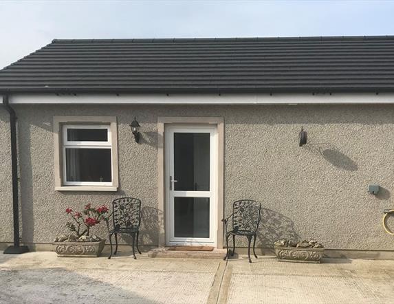 Image is of front of the property with wrought iron chairs at either side of the front door