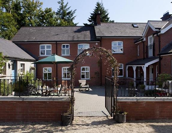 Image shows front of property with archway entrance and small courtyard with seating area