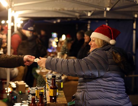 Lady with Santa hat selling at a stall at Christmas Market