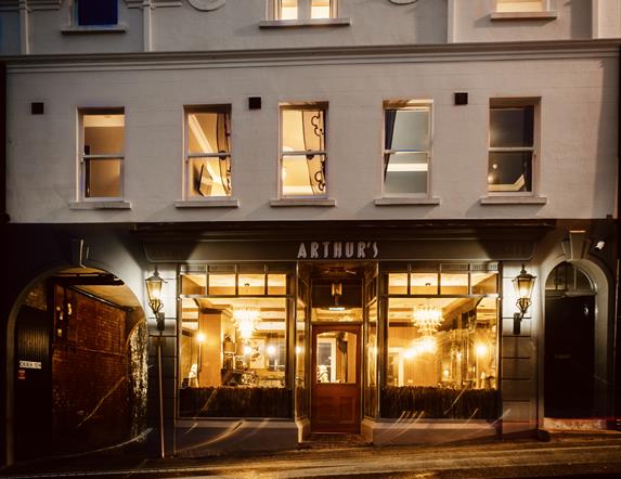 Picture of the exterior front of Arthur's Guest House lit up at night