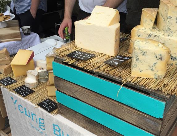 Image shows a stall of various cheeses at the Inns Cross Market