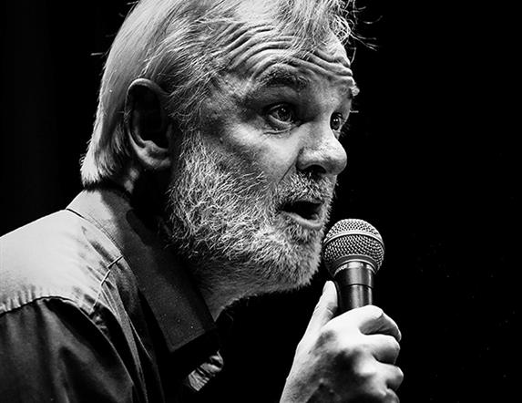 Black and white picture of Tim McGarry with a microphone