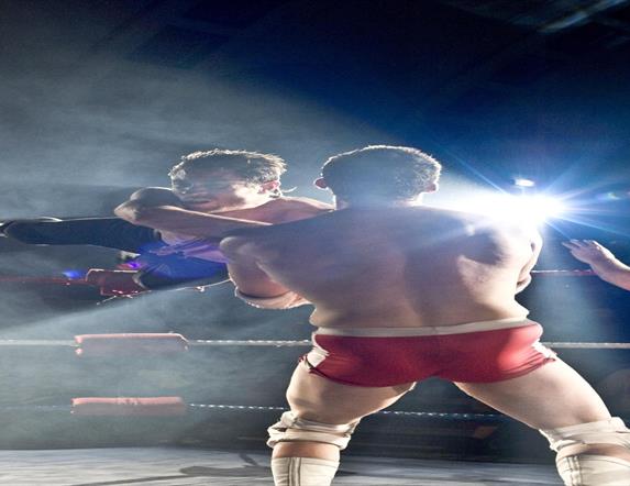 Two wrestlers on stage with a referee