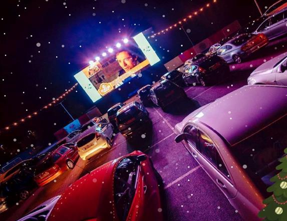 Image shows rows of cars at a drive-in movie