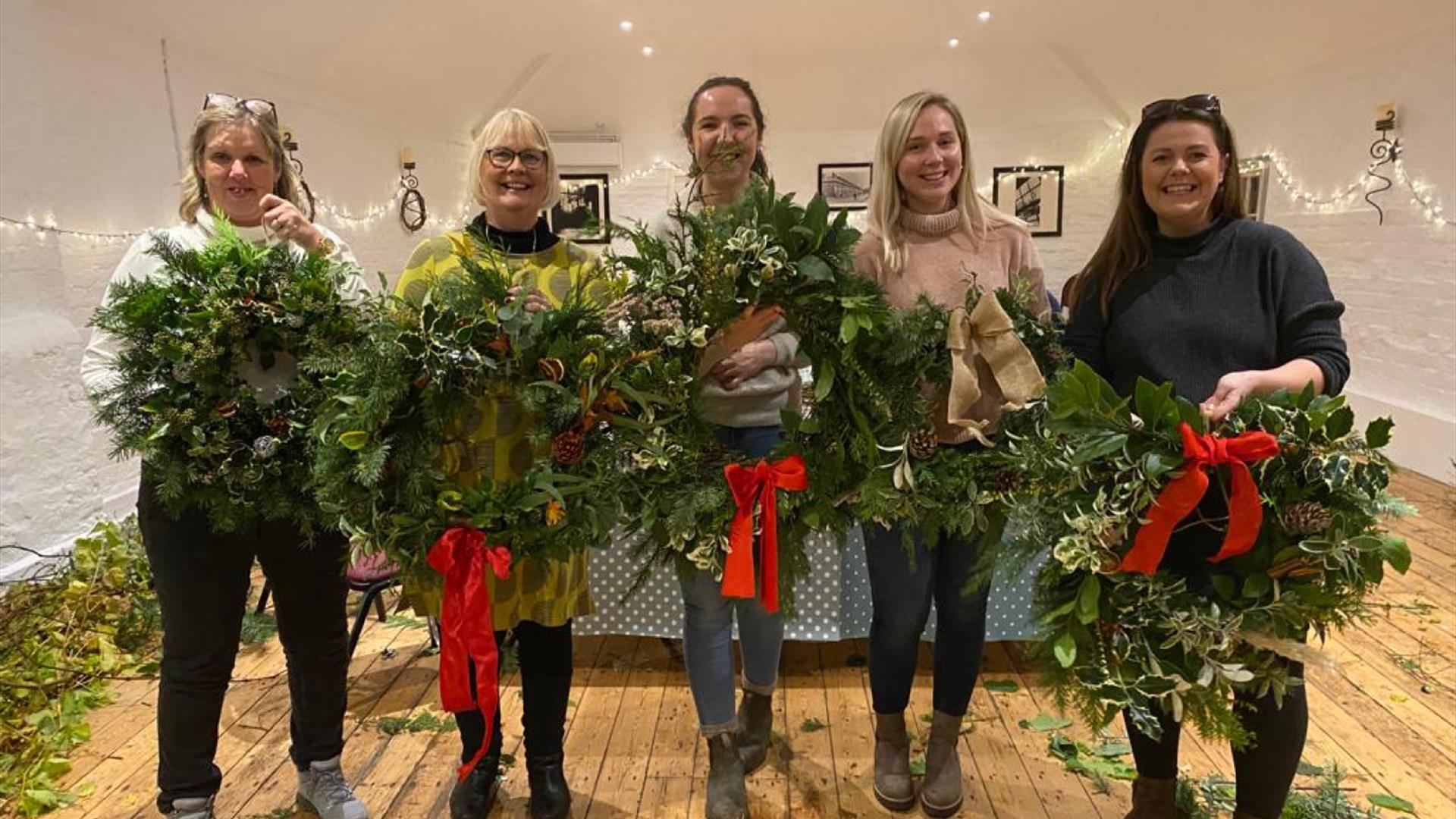 Image shows 5 people holding their decorated wreaths.