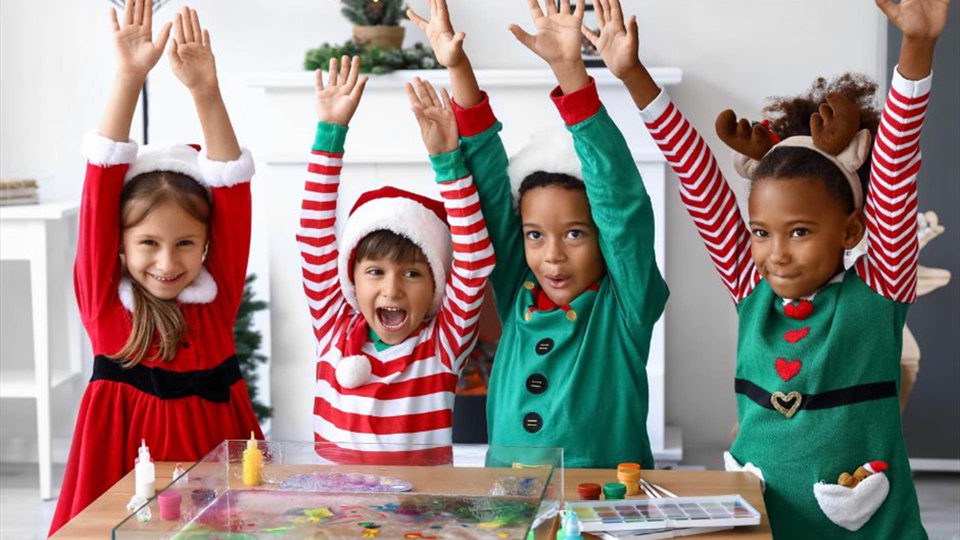 Image is of children dressed up for Christmas and doing arts and crafts