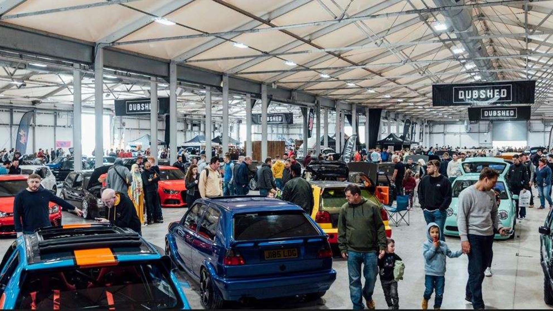 Image is of various cars and visitors at DUBSHED show in the Eikon Exhibition Centre LIsburn