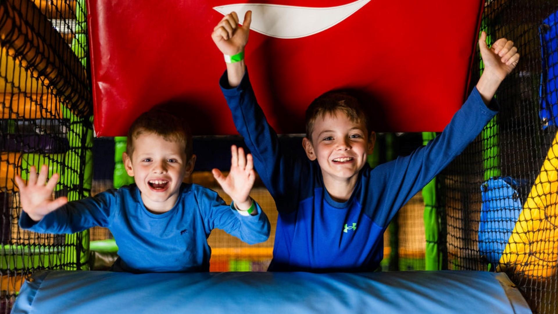 Image shows two boys dressed in blue with arms raised having fun in High Rise play area