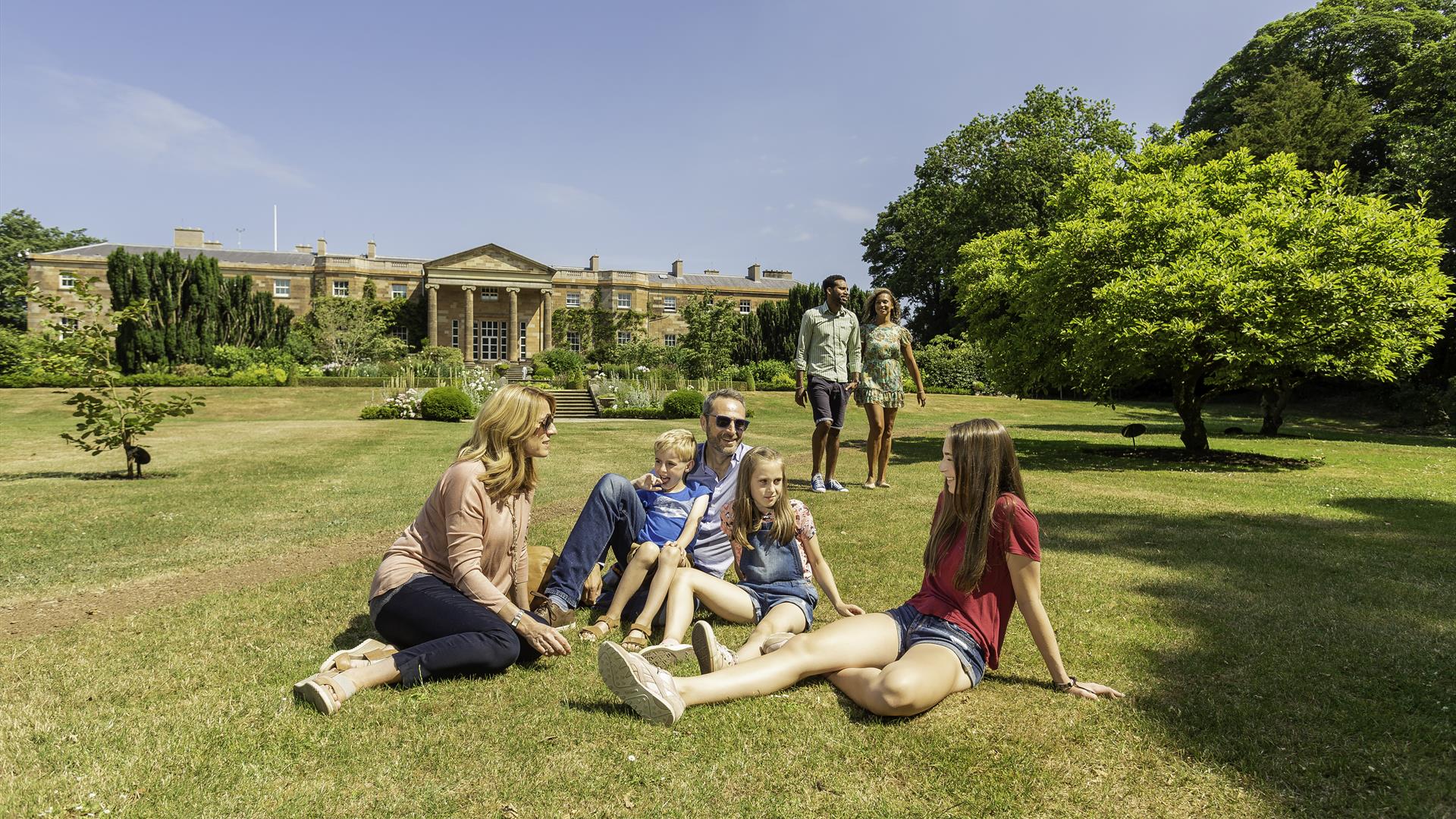 Family sitting on grass in front of Hillsborough Castle