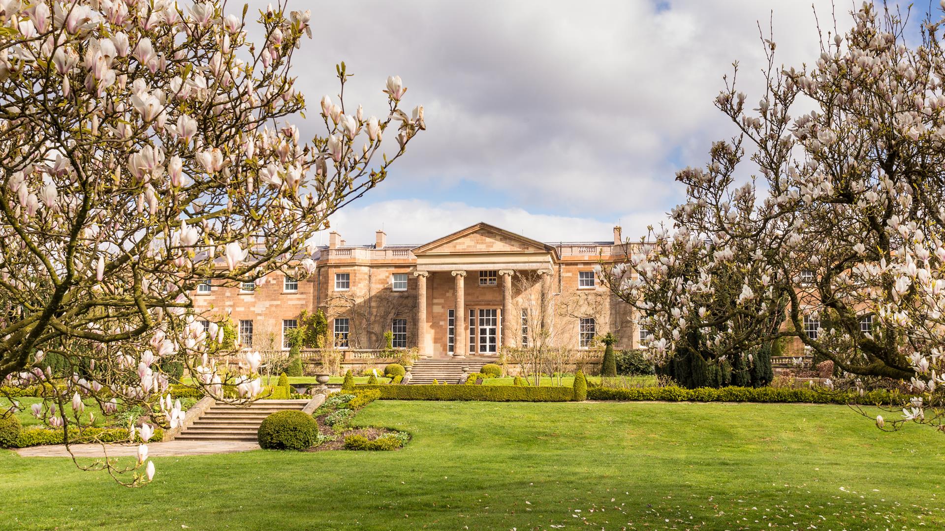 Image is the rear of Hillsborough Castle with trees and lawn in front