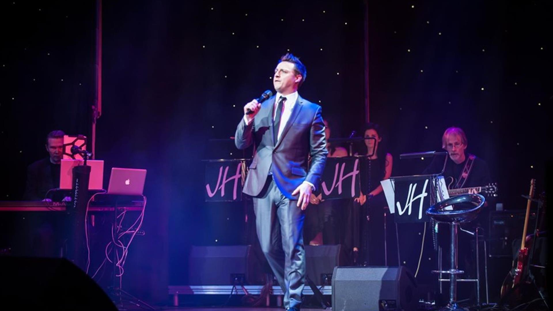 Image is of singer James Huish performing on stage