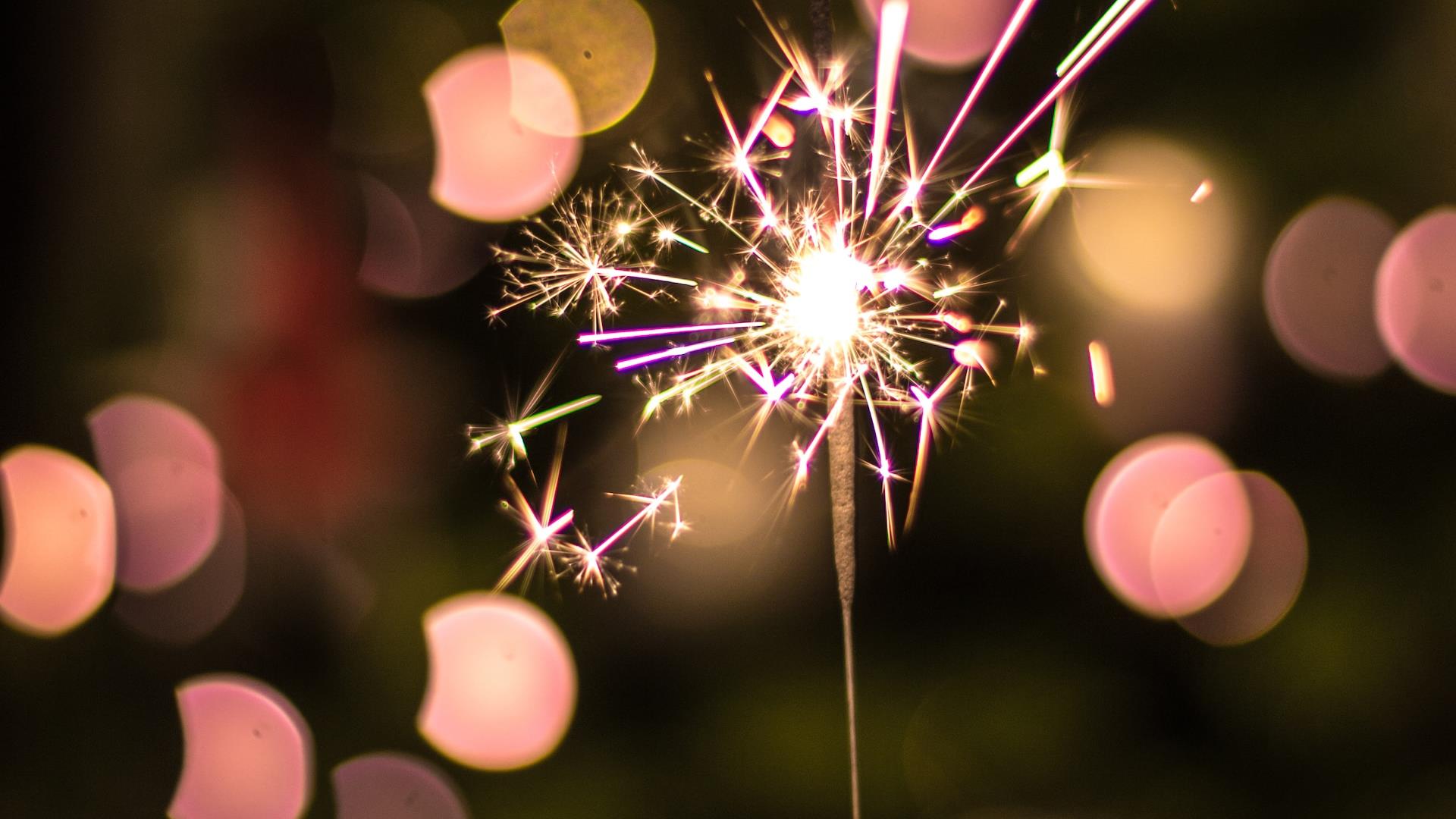 Hand holding a sparkle up against Christmas lights