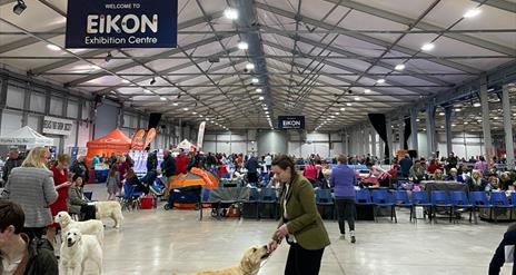 Image is of dogs and owners in the Eikon 
Exhibition Centre dog show