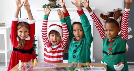 Image is of children dressed up for Christmas and doing arts and crafts