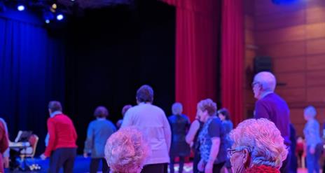 Tea dance participants seated and dancing