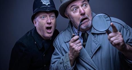 Two men one dressed as a policeman and one as a Sherlock Holmes