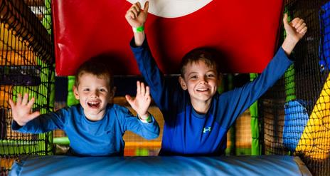 Image shows two boys dressed in blue with arms raised having fun in High Rise play area