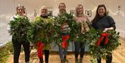 Image shows 5 people holding their decorated wreaths.