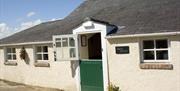 Image shows front of cottage with green stable door as entrance