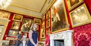 Image shows visitors viewing various paintings on the wall in one of the visiting rooms