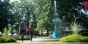 Couple walking through Castle Gardens holding hands beside fountain