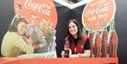 Image is of a member of staff at Coca-Cola Experience enjoying a bottle of Coca-Cola