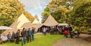 Image shows beer tents at Hilden Brewery with people standing at an event