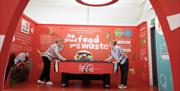 Image is of visitors playing a game in the Coca-Cola Visitor Experience