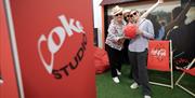 Image is of visitors posing with a red ball and sign showing Coke Studio