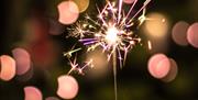 Hand holding a sparkle up against Christmas lights