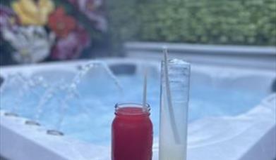 Image is of a hot tub with a glass drink sitting on the side