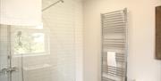 Image shows bathroom with large walk in shower and tall radiator