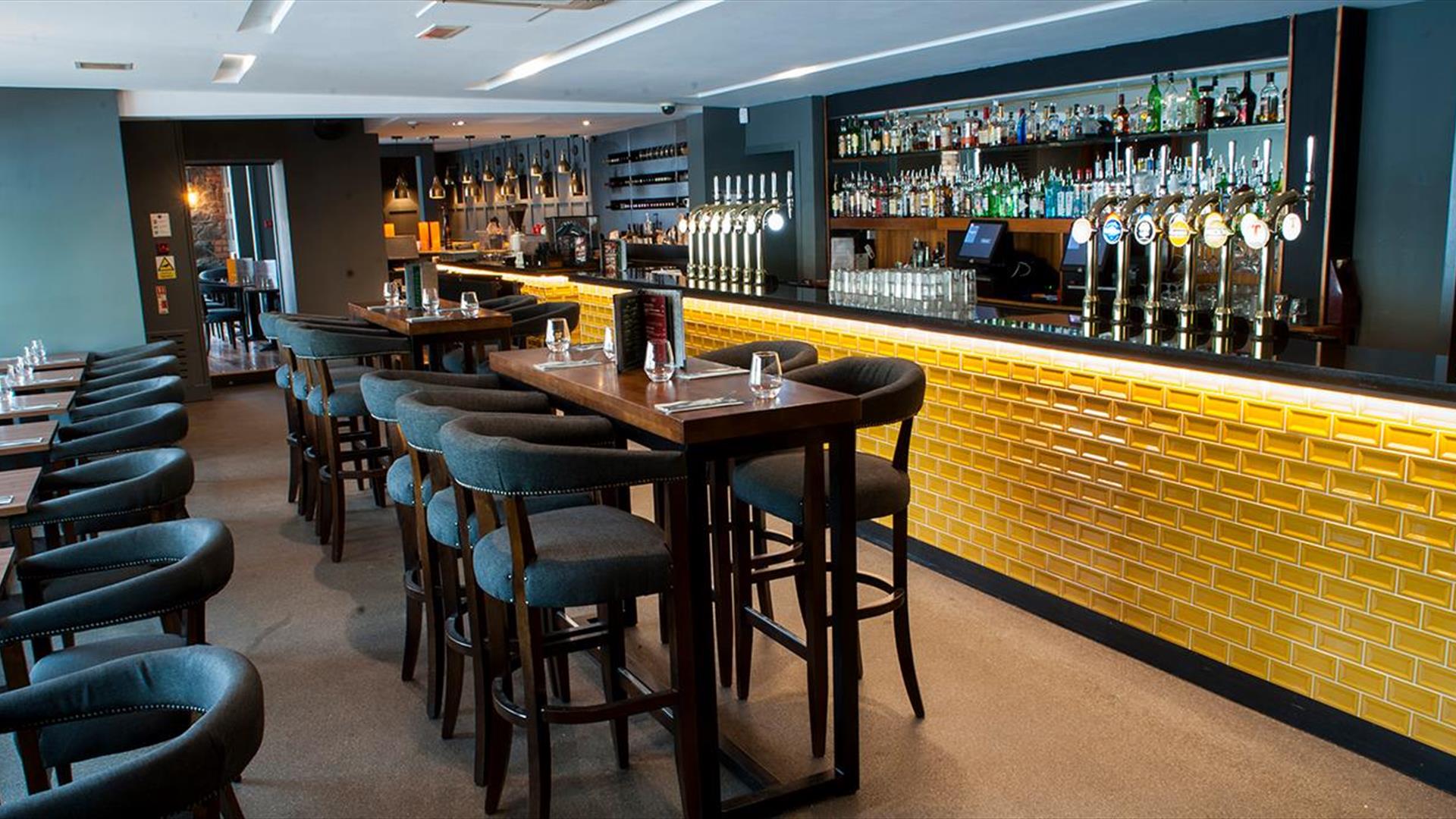 Image shows the Cardan bar with yellow brick front and an extensive seating area with low seating and tables and higher bar stool area