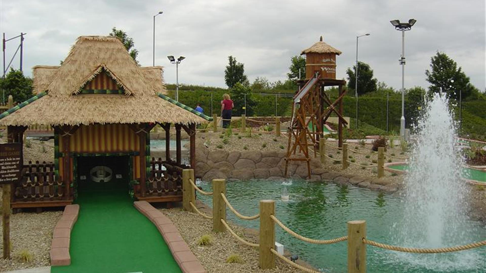 Image shows golf putting area with small lake and fountain Image shows golf putting area with small lake and fountain