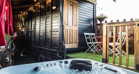 Image shows hot tub with patio and entrance to horse truck with door closed